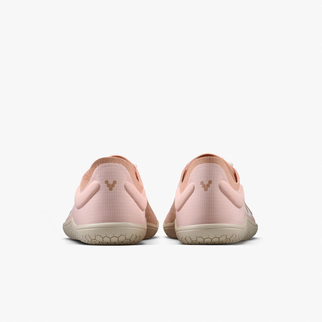 The VIVOBAREFOOT Primus Lite IV (Women's) in light pink features beige soles and a subtle heel logo, seen from the back on a plain white background. These barefoot trainers are designed to promote natural movement.