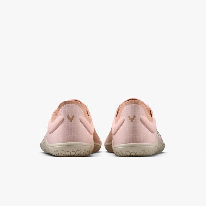 The VIVOBAREFOOT Primus Lite IV (Women's) in light pink features beige soles and a subtle heel logo, seen from the back on a plain white background. These barefoot trainers are designed to promote natural movement.