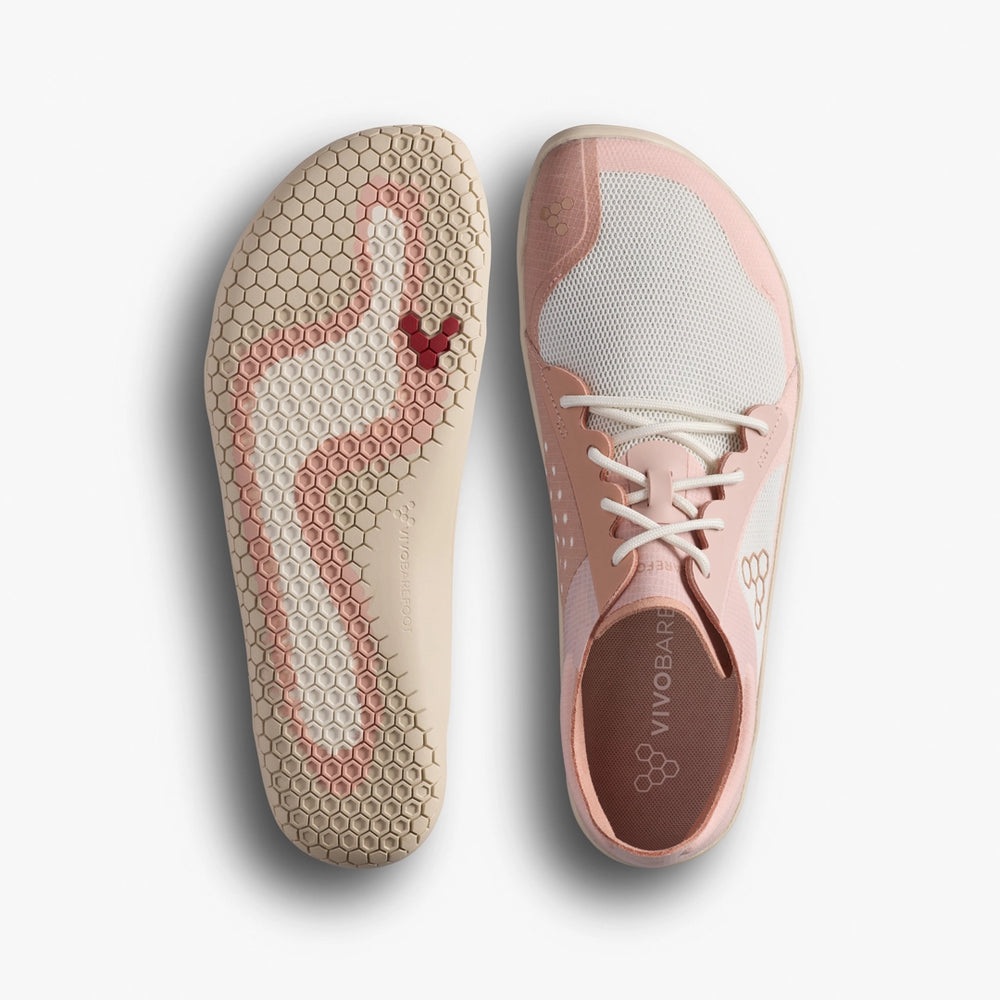 The VIVOBAREFOOT Primus Lite IV (Women's) barefoot trainers in pink and white are shown from the side and sole; the hexagonal-patterned sole has a reddish stain, with laces and the Vivobarefoot logo visible on the insole.