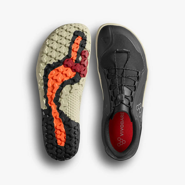 Top and bottom views of the women's VIVOBAREFOOT Primus Trail III All Weather FG, a black vegan trail shoe featuring a beige, orange, and red hexagonal-patterned sole. The water-resistant sneaker has a red insole labeled “VIVOBAREFOOT” and is designed for durability and comfort on any adventure.