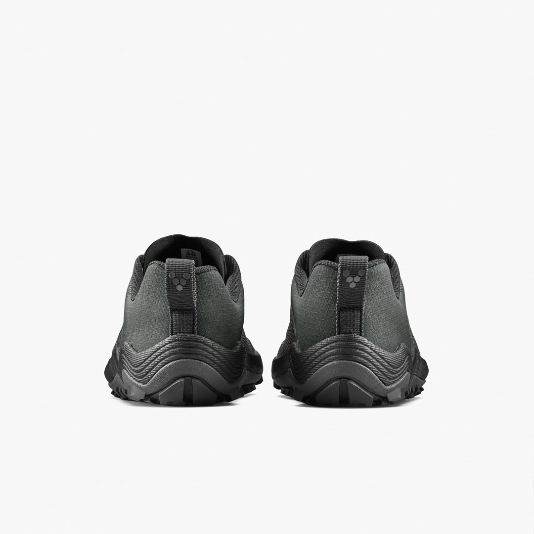 The VIVOBAREFOOT Primus Trail Flow (Women's) trail shoes in dark green and black are shown from the back, highlighting their textured soles and pull tabs against a plain white background.