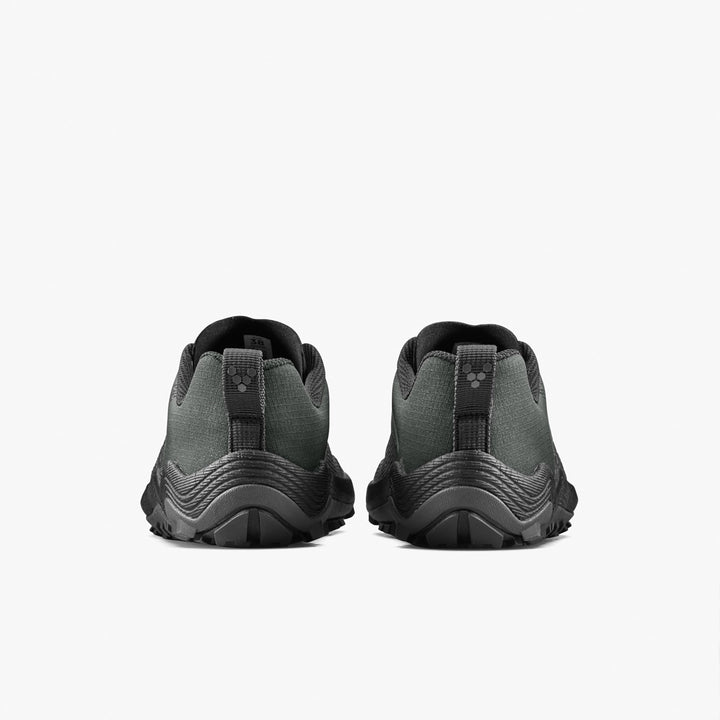 The VIVOBAREFOOT Primus Trail Flow (Women's) trail shoes in dark green and black are shown from the back, highlighting their textured soles and pull tabs against a plain white background.