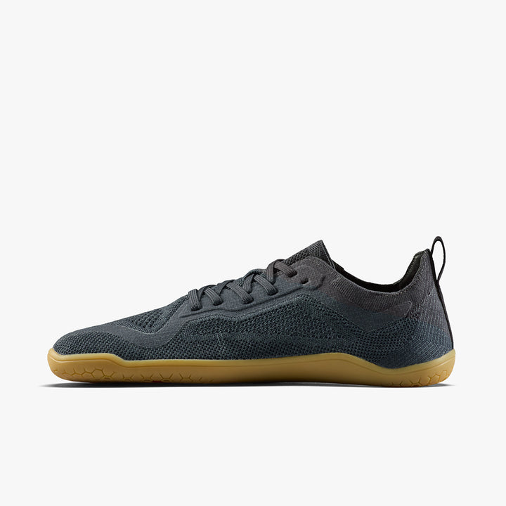 The STRIDE LAB USA Primus Lite Knit Natural (Women's) is a minimalist dark gray barefoot performance trainer with a mesh upper, black heel tab, recycled PU insole, and light brown rubber sole, shown in side profile on a white background.