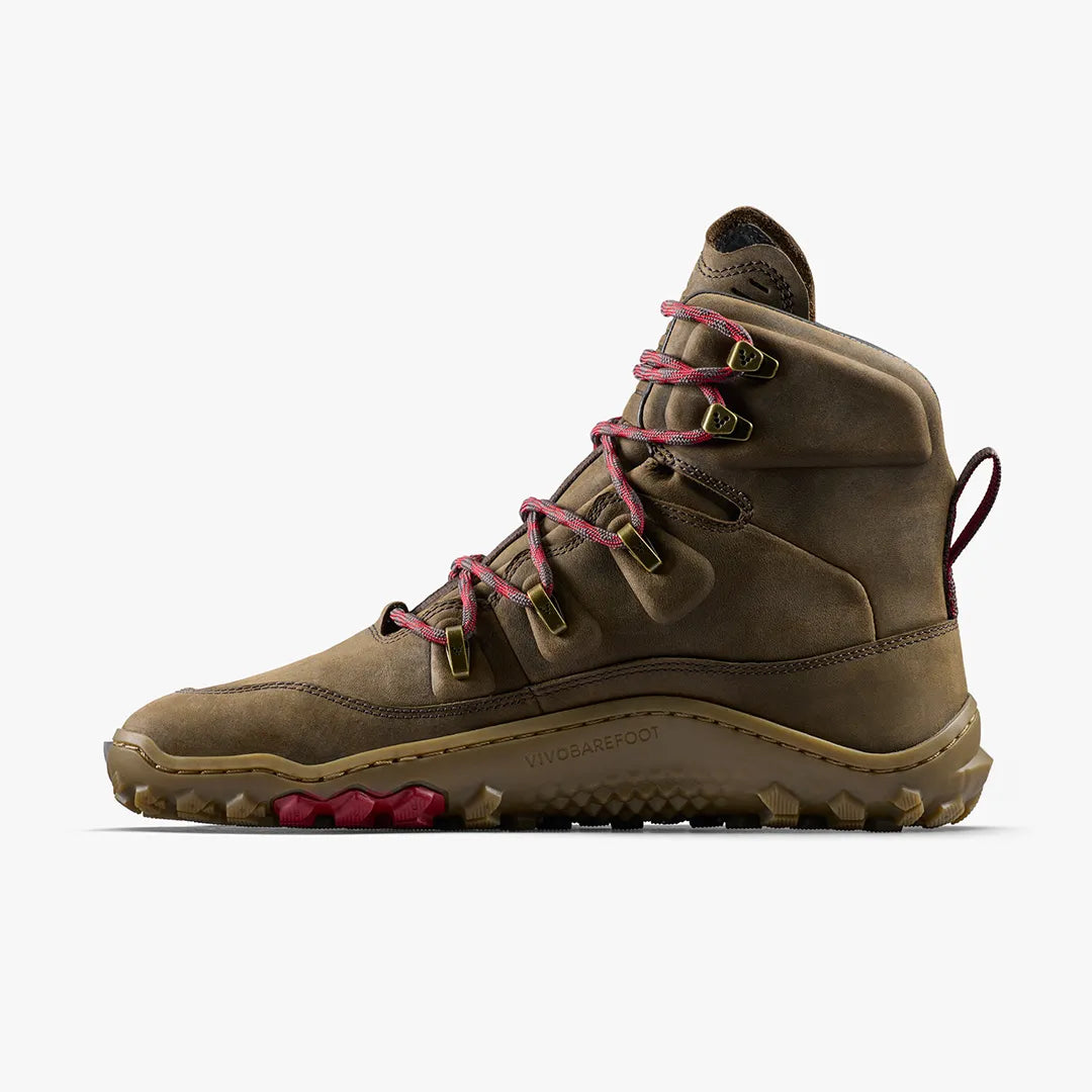 The VIVOBAREFOOT Tracker Leather AT II (Women's) is a brown high-top barefoot hiking boot with red laces, rugged sole, metal eyelets, reinforced stitching, and a thermal insole for durable all-terrain comfort. Side view on white background.