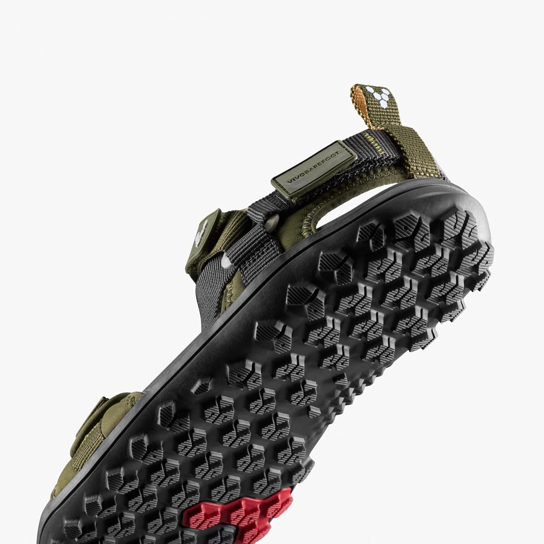 A close-up of the Tracker Ora Sandal (Men's) by VIVOBAREFOOT in olive green, featuring black straps and a textured hexagonal sole pattern for enhanced all-terrain traction.
