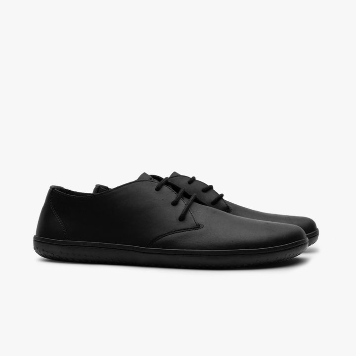 A pair of VIVOBAREFOOT Ra IV (Men's) minimalist black barefoot Oxfords, made from Wild Hide leather with a low-profile, flexible Gobi outsole, shown side by side on a plain white background.