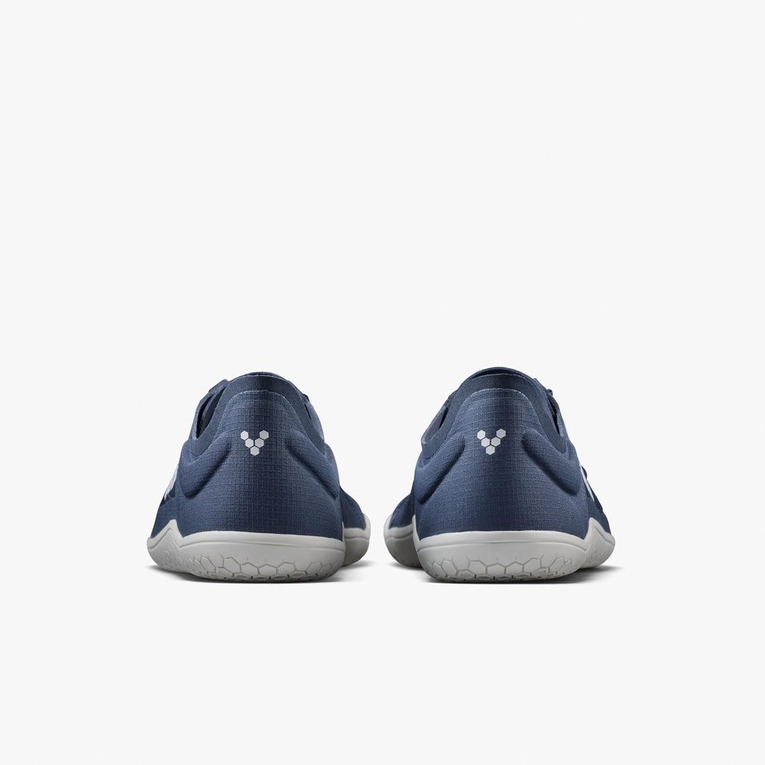 The VIVOBAREFOOT Primus Lite IV (Men's) barefoot trainers in blue are shown from the back against a plain white background, featuring white soles and a small white triangular heel logo to support natural movement.