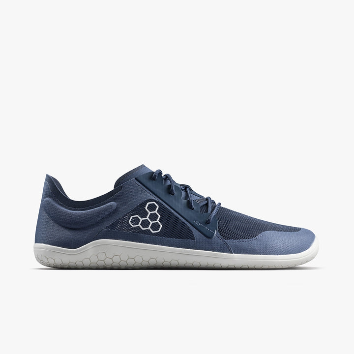 The VIVOBAREFOOT Primus Lite IV (Men's) is a blue minimalist barefoot trainer with a white sole, mesh upper, and hexagonal side logo, designed for natural movement, shown in side view on a plain white background.