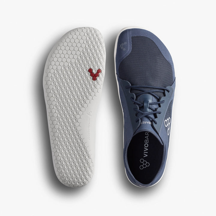 Top and bottom view of the VIVOBAREFOOT Primus Lite IV (Men’s), a minimalist blue barefoot trainer with a white hexagonal-patterned sole, red hexagon detail near the toe, and branding. Designed to promote natural movement.
