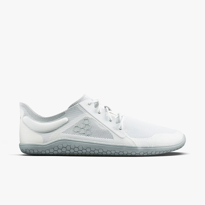 The VIVOBAREFOOT Primus Lite IV (Men's) is a minimalist white barefoot running shoe with a mesh upper, lace-up closure, and thin, flexible gray hex-pattern sole for lightweight breathability.