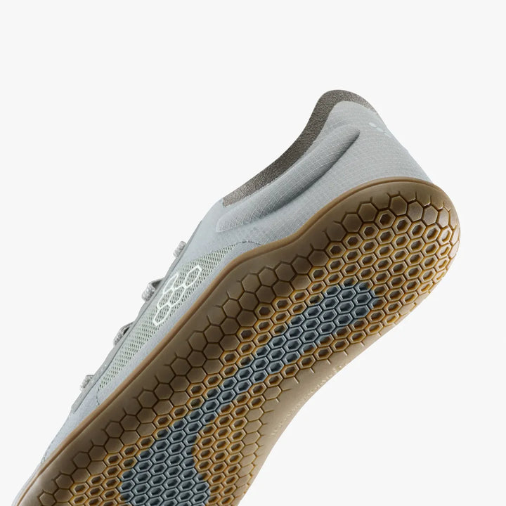 Close-up of the light blue recycled material fabric upper and tan hexagonal-patterned rubber sole of a VIVOBAREFOOT Primus Lite IV (Men’s) vegan running shoe.