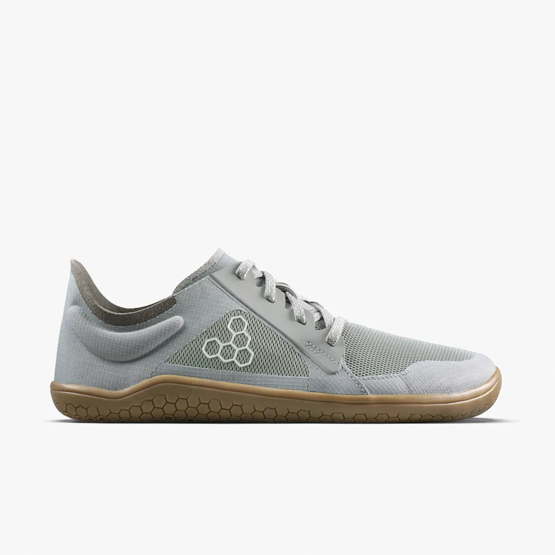 A grey VIVOBAREFOOT Primus Lite IV (Men’s) lace-up barefoot training sneaker with a gum-colored rubber sole and a white hexagonal logo on the side.