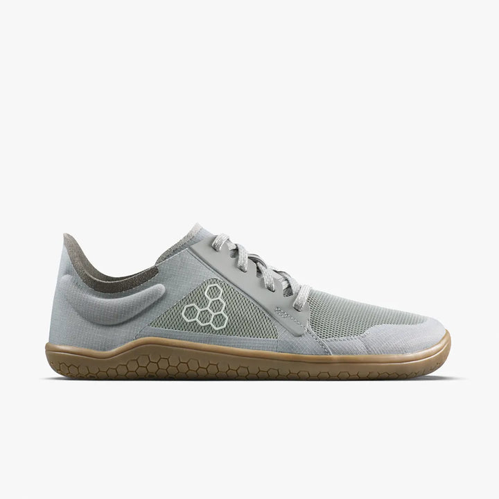 A grey lace-up VIVOBAREFOOT Primus Lite IV (Women’s) minimalist sneaker made from recycled materials, featuring a tan rubber sole and a white hexagonal logo on the side.