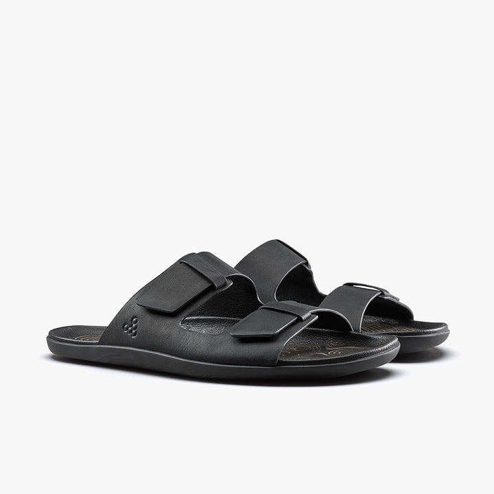 The VIVOBAREFOOT Sensus Yin Slide (Men's) sandals, in black Taro leather with two adjustable straps and a contoured Earthfoam footbed, are shown on a white background.
