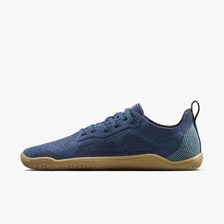 The VIVOBAREFOOT Primus Lite Knit Natural (Men’s) sneaker, inspired by barefoot performance trainer design, is displayed on a white background. This blue athletic shoe features a gum sole, textured pattern, lace-up front, and a pull tab at the heel.