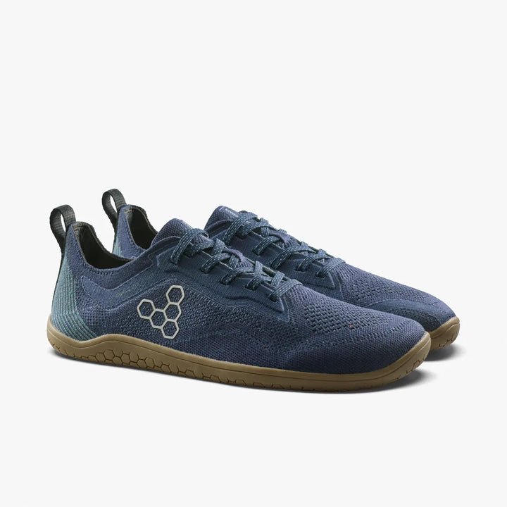 The VIVOBAREFOOT Primus Lite Knit Natural (Men’s) shoes, featuring blue mesh fabric, black pull tabs, gum soles, and a hexagonal logo on the side, are natural workout shoes engineered for enhanced comfort and support. They are displayed on a plain white background.