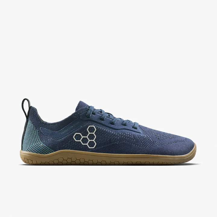 The VIVOBAREFOOT Primus Lite Knit Natural (Men’s) is a blue minimalist sneaker featuring a tan sole, hexagonal side logo, mesh knit fabric reminiscent of sock shoes, blue laces, and a black heel pull tab, displayed on a white background.