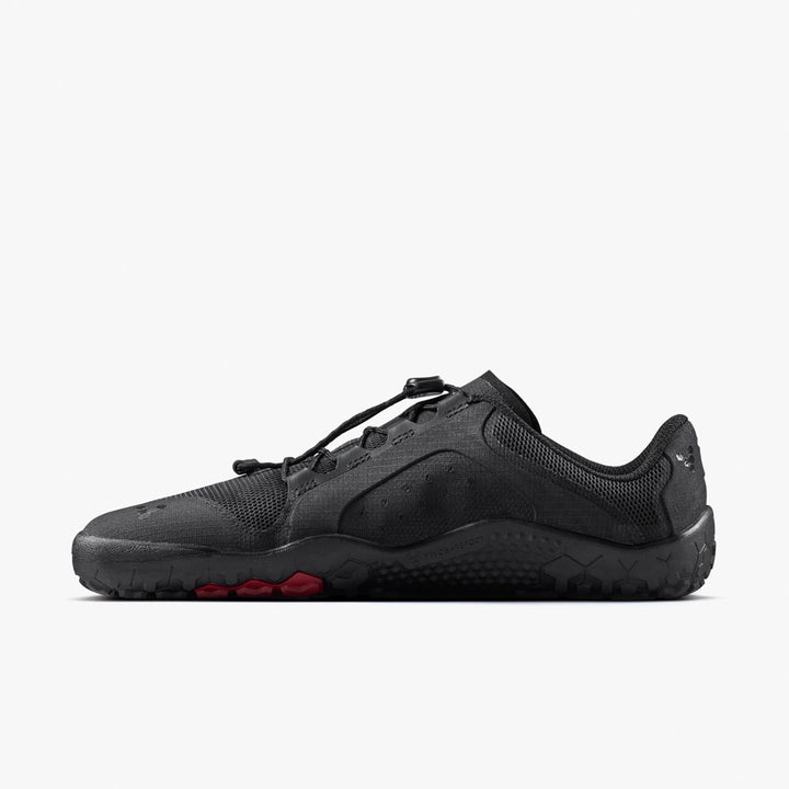 The VIVOBAREFOOT Primus Trail FG 3.5 (Men's) is a black, low-profile all-terrain trainer with a breathable mesh upper, rugged sole with red toe accents, and lace toggle, shown from the side on a plain white background.