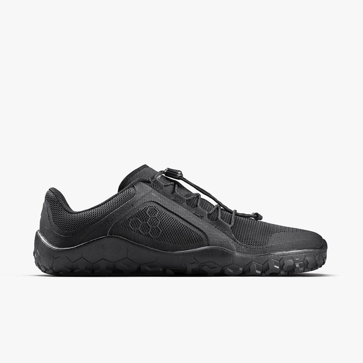 The VIVOBAREFOOT Primus Trail FG 3.5 (Men's) is a black all-terrain trainer with a breathable mesh upper, toggle lace system, and hexagonal patterned sole, shown in profile against a plain white background.
