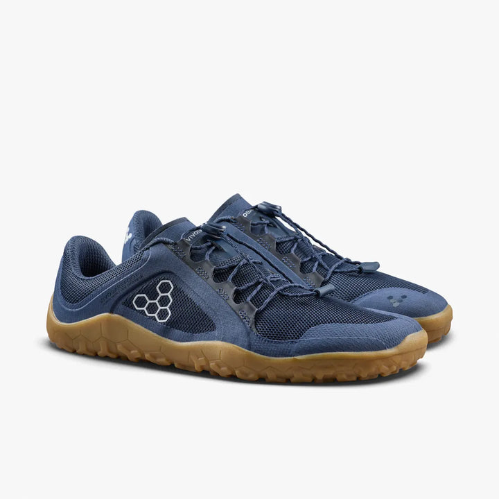The VIVOBAREFOOT Primus Trail FG 3.5 (Men’s), featuring blue breathable mesh uppers, gum rubber soles, and a white geometric logo on the side, is displayed against a plain white background.