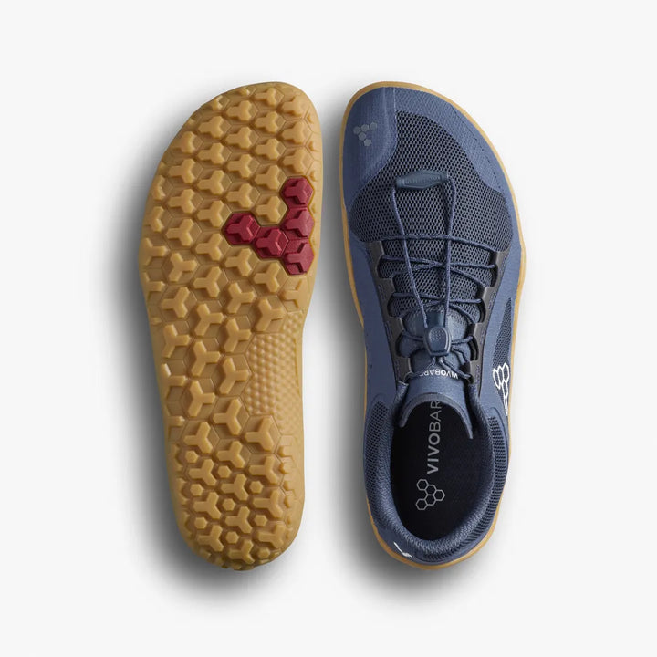 A pair of blue VIVOBAREFOOT Primus Trail FG 3.5 (Men’s) trainers, one highlighting the textured gum sole with red hexagonal tread designed for a firm ground outsole, and the other displaying a top view featuring laces, the VIVOBAREFOOT logo, and a breathable mesh upper.