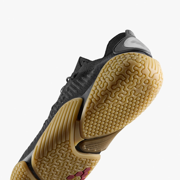 A close-up of the Motus Flex Natural (Men's) by VIVOBAREFOOT shows its textured, light brown natural rubber outsole with intricate grip patterns, set against a plain white background.