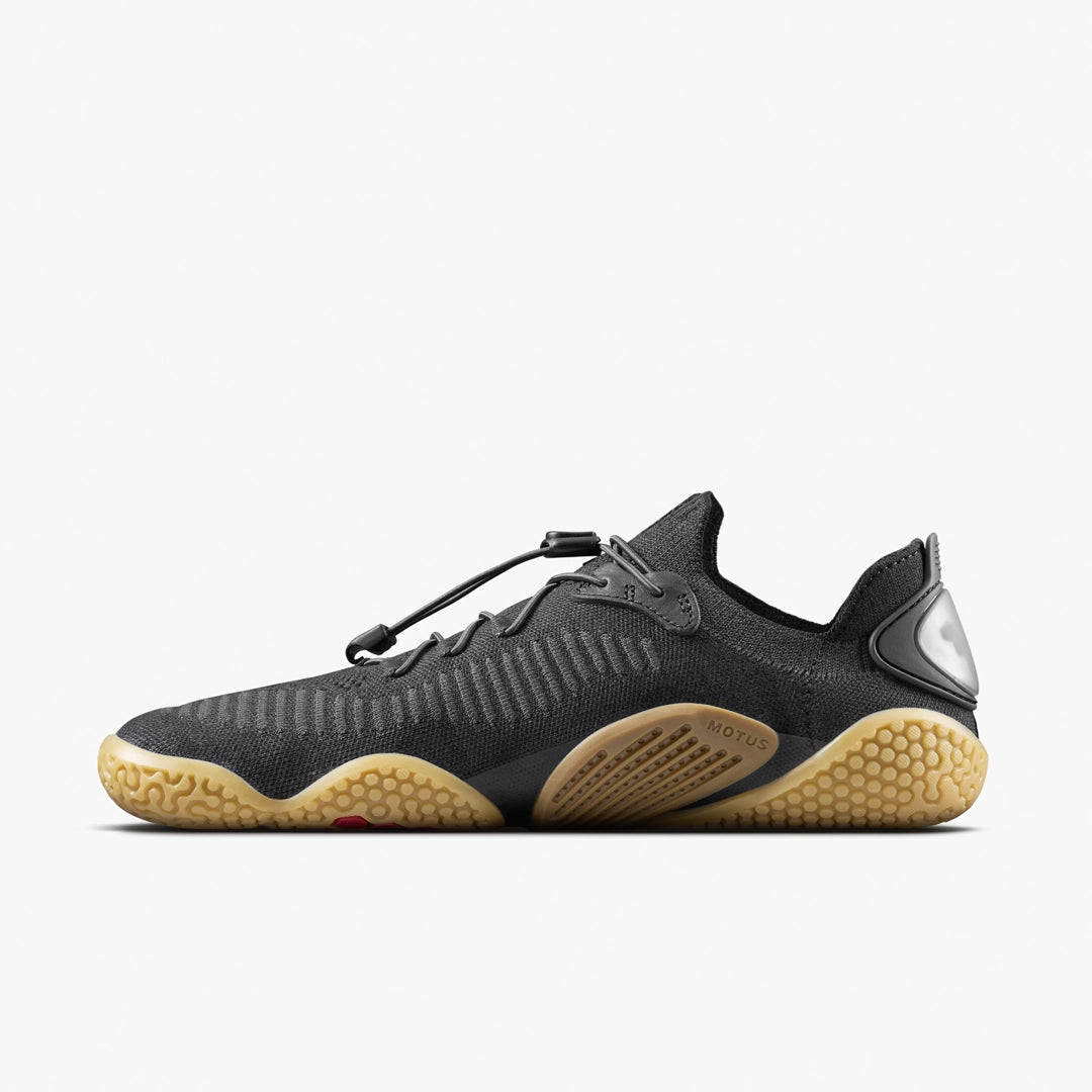 A side view of the VIVOBAREFOOT Motus Flex Natural (Men's) shows its dark grey upper, wavy natural rubber outsole, toggle lace system, and reflective heel detail—ideal for calisthenics or primal movement—displayed on a white background.