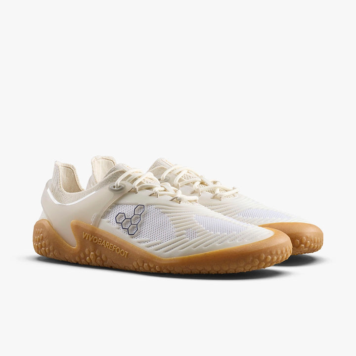 The VIVOBAREFOOT Motus Strength II (Women's) trainers feature off-white and beige mesh uppers, gum soles, and side logos—ideal barefoot shoes for functional fitness, shown on a white background.