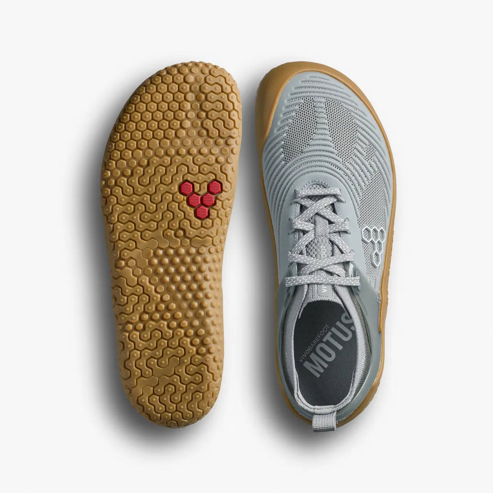 A pair of VIVOBAREFOOT Motus Strength II (Men’s) barefoot strength trainers shown from the top and the underside, highlighting the grey breathable mesh upper and the textured gum rubber sole.