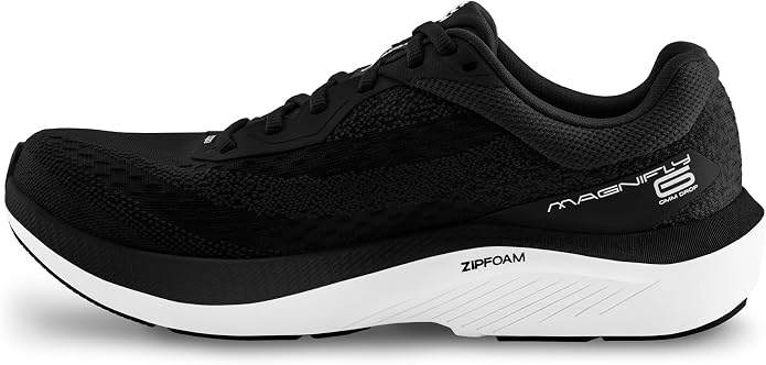 A black women’s athletic running shoe by TOPO, the Magnifly 6 features prominent ZIPFOAM branding on the side, a thick white sole, and black laces. Shown in a left-side profile view, it’s perfect for fans of cushioned running shoes seeking both comfort and style with every stride.