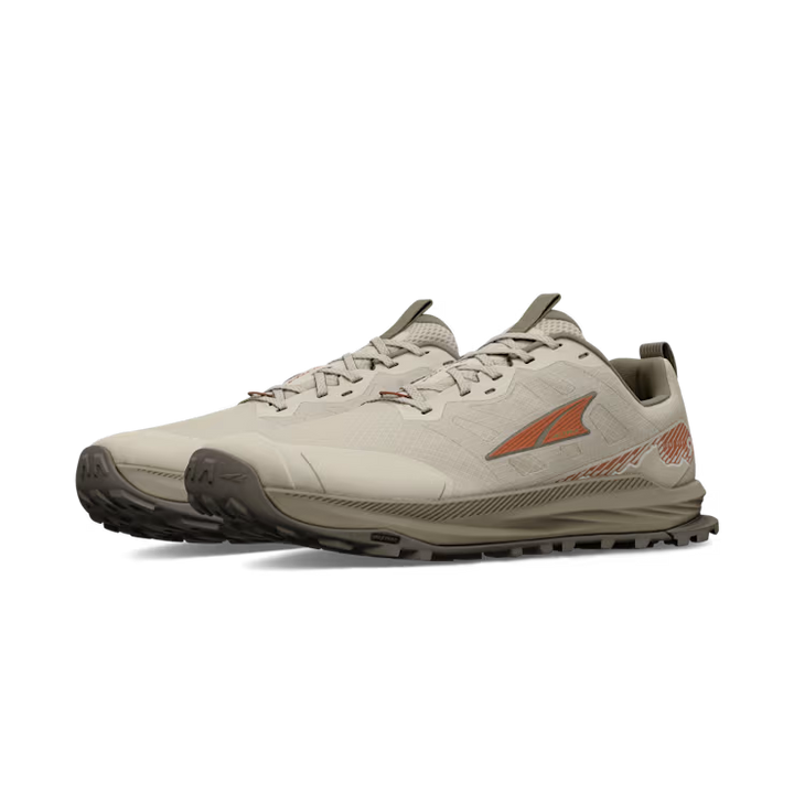 The ALTRA Lone Peak 9 Wide (Men’s) is a beige trail running shoe with brown outsoles and orange accents, shown at an angle with the left shoe in front. It features a rugged sole, low-cut design, and roomy toe box for tough terrain comfort.