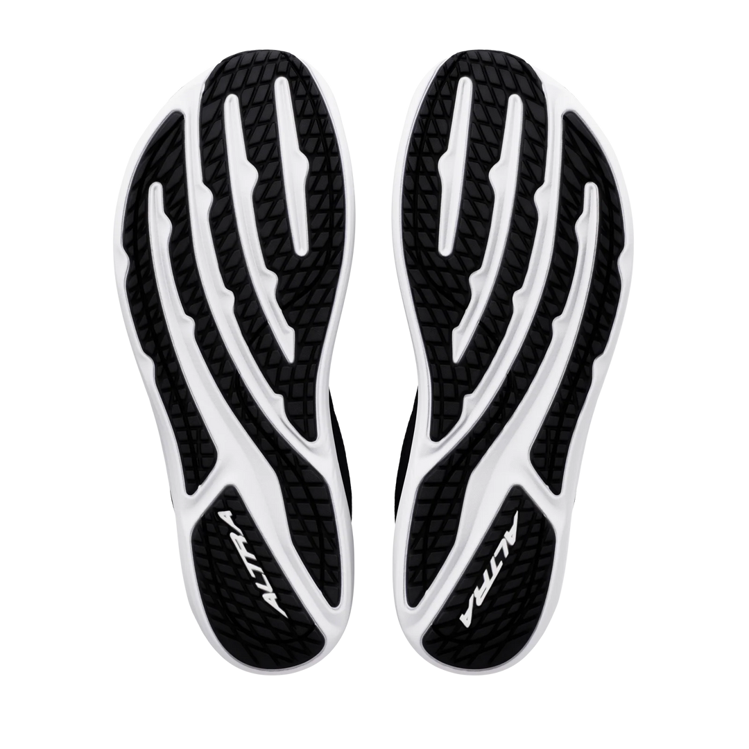 The black and white soles of the ALTRA Escalante 5 (Men’s) shoes are displayed from the bottom against a white background, showcasing textured tread patterns and the ALTRA logo on each sole. Designed with zero drop construction and ALTRA’s signature FootShape Fit for natural comfort, these shoes are a standout in the Escalante 5 collection.