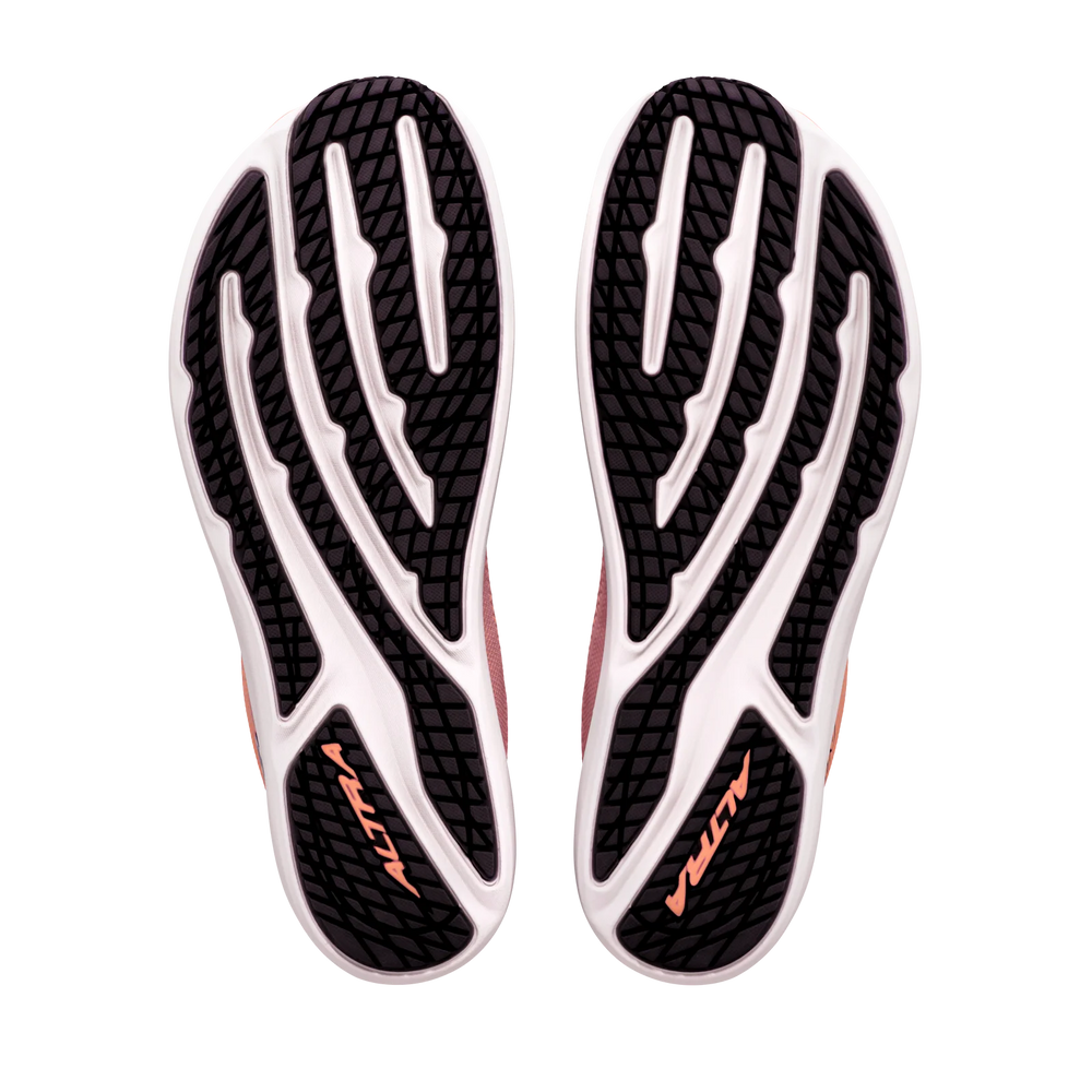 The image displays the black and white outsoles of the ALTRA Escalante 5 (Women’s) athletic shoes, each featuring “ALTRA” in orange text. The tread pattern combines curved and straight lines, emphasizing their performance-driven design. These shoes stand out with their Altra EGO midsole, offering responsive cushioning with every step.