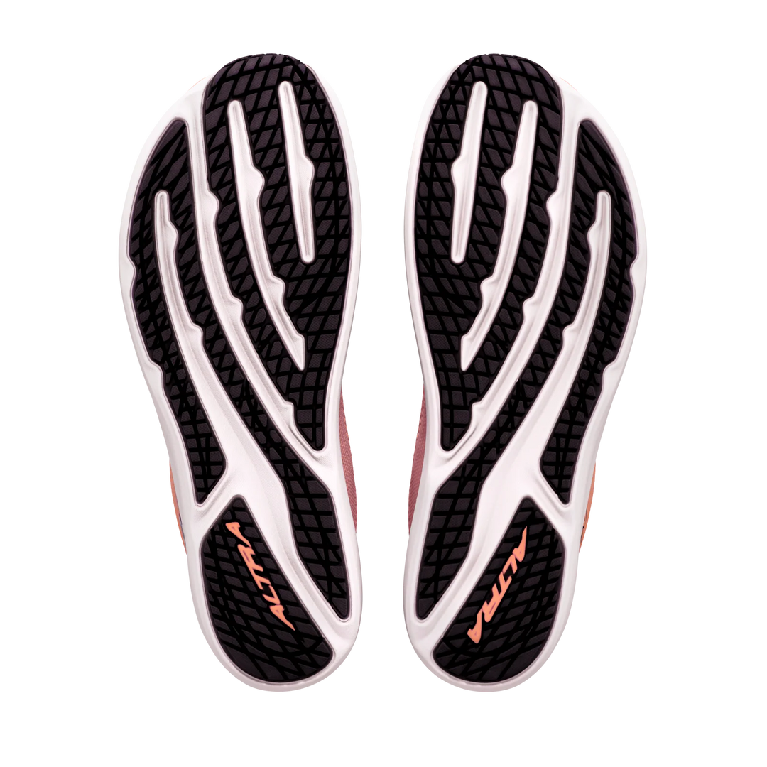 The image displays the black and white outsoles of the ALTRA Escalante 5 (Women’s) athletic shoes, each featuring “ALTRA” in orange text. The tread pattern combines curved and straight lines, emphasizing their performance-driven design. These shoes stand out with their Altra EGO midsole, offering responsive cushioning with every step.