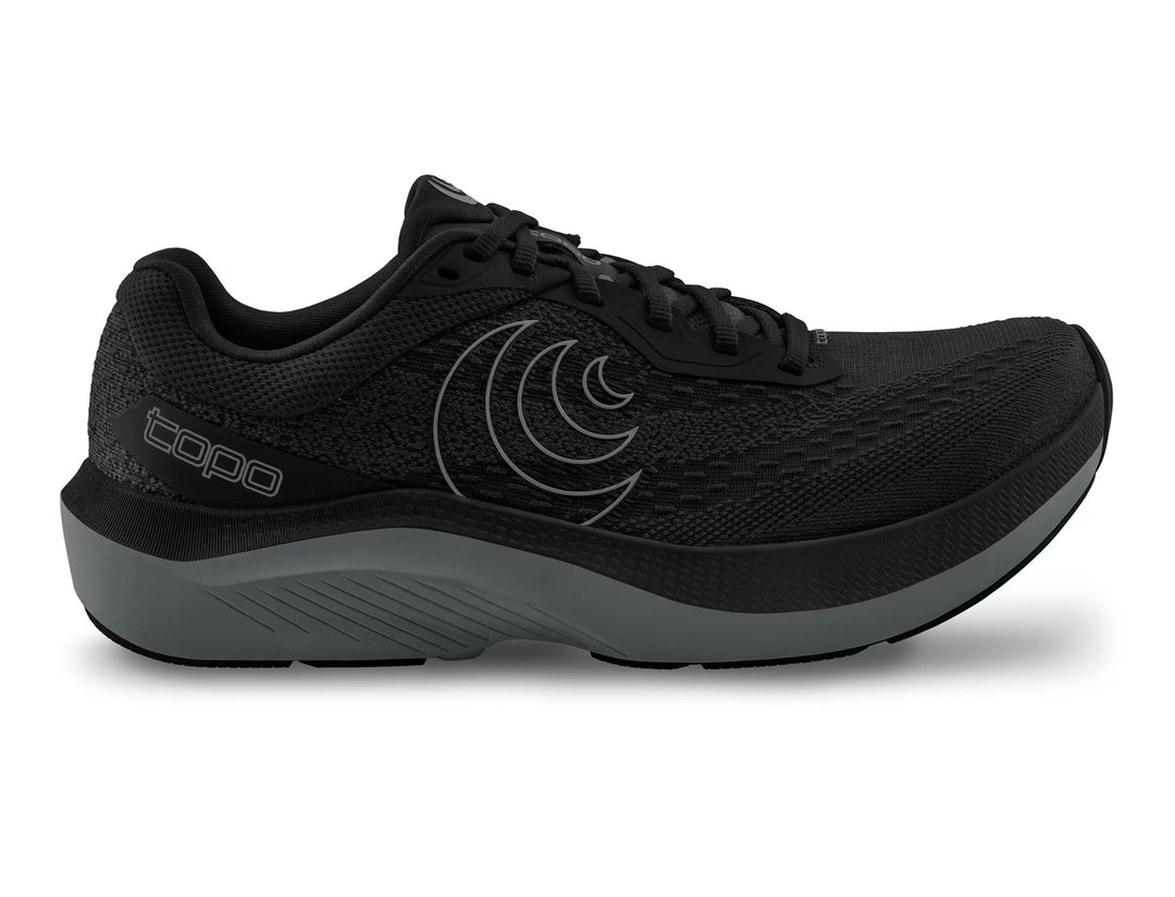 The TOPO Magnifly 6 (Men's) is a black running shoe with a gray sole, black laces, the TOPO logo on the side, a patterned mesh upper, and ZipFoam midsole for responsive cushioning in a sleek, modern design.