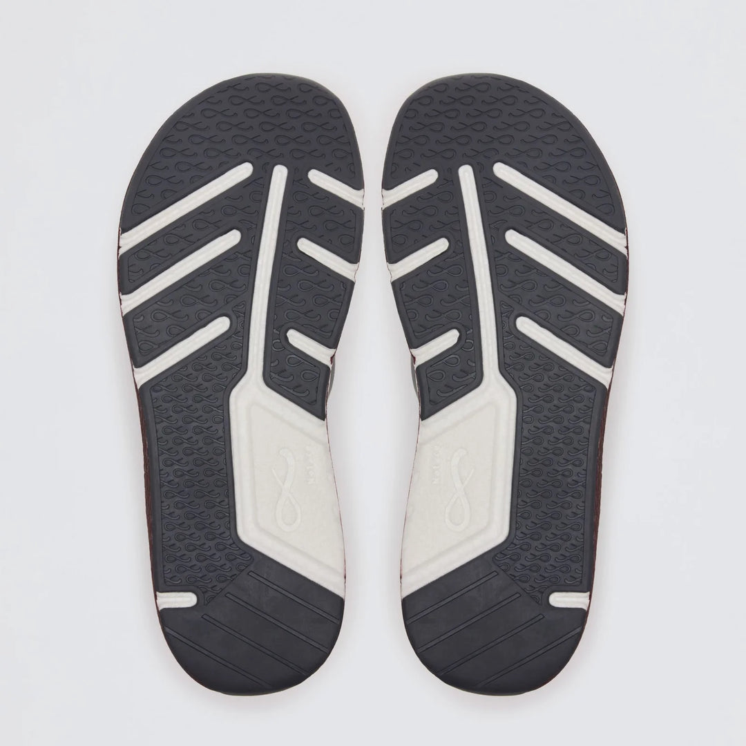 A pair of Michi 1 (Men’s) shoes by Notace, featuring dark and light-colored soles positioned side by side to showcase their textured tread patterns and infinity symbol detailing, perfectly illustrates these lightweight road-to-gym shoes designed for all-day comfort—all set against a clean white background.