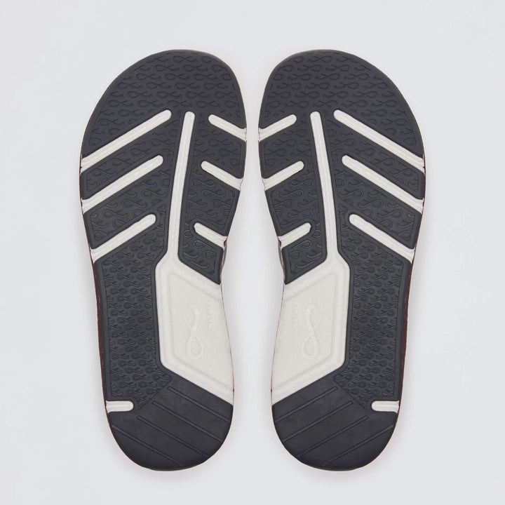 A pair of Michi 1 (Men’s) shoes by Notace, featuring dark and light-colored soles positioned side by side to showcase their textured tread patterns and infinity symbol detailing, perfectly illustrates these lightweight road-to-gym shoes designed for all-day comfort—all set against a clean white background.