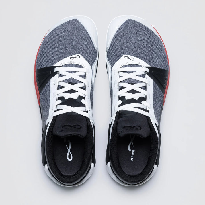 A top-down view shows the Notace KOTO 1 (Men's) gym shoes, featuring white laces, grey and black uppers with red side accents, and a white infinity symbol on the tongue. They’re designed for multidirectional control and rest side by side on a light background.