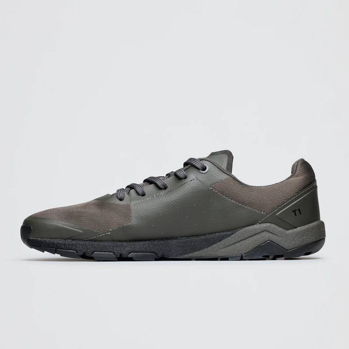 A side view of the Notace Yama T1 (Women's), a modern low-top trail shoe in gray and olive green with textured panels, lace-up front, black rubber sole for grip, and a “T1” marking near the heel.