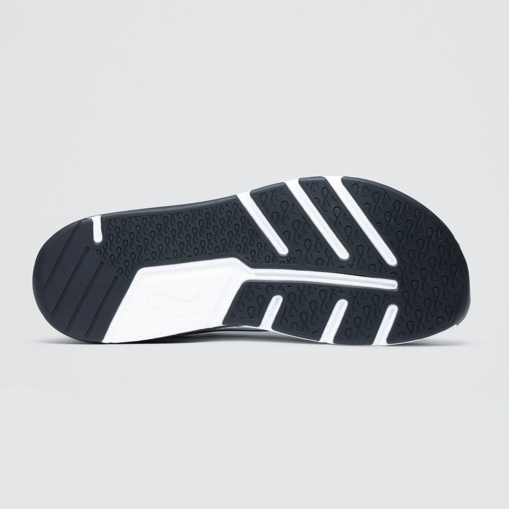 A close-up of the Notace Michi 1 (Women's) lightweight road-to-gym shoe outsole displays its textured tread with wavy grooves and white rubber traction sections, set against a plain light gray background.