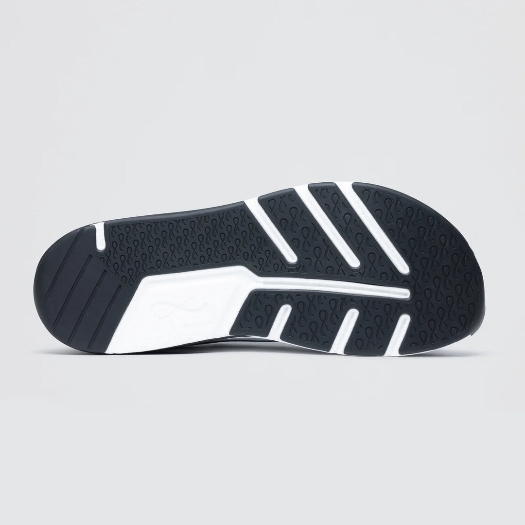 A close-up of the Notace Michi 1 (Women's) lightweight road-to-gym shoe outsole displays its textured tread with wavy grooves and white rubber traction sections, set against a plain light gray background.