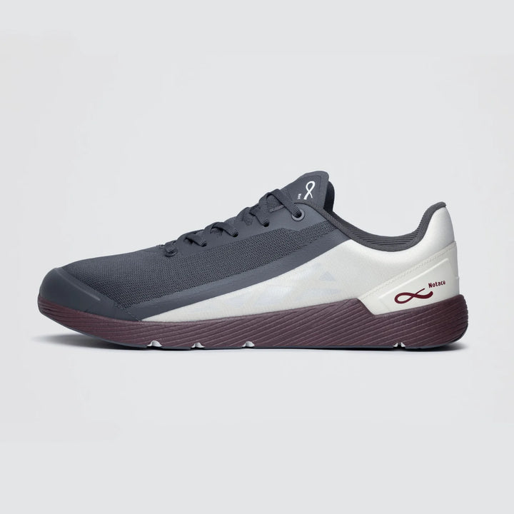 The Notace Michi 1 (Men’s) is an athletic sneaker in black, white, and maroon, pictured from the left side with a dark sole and subtle logo accents near the heel and on the tongue. This flexible training shoe is equipped with an eTPU midsole for superior comfort and responsiveness throughout your workouts.