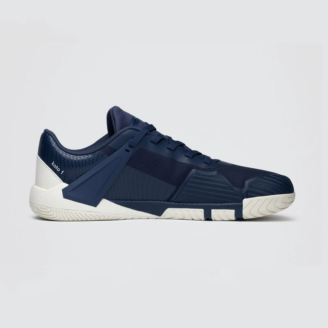 The Notace Koto 1 (Women’s) athletic gym shoe, in navy blue with white heel and sole accents and engineered for multidirectional control, is displayed from the side against a plain light gray background.