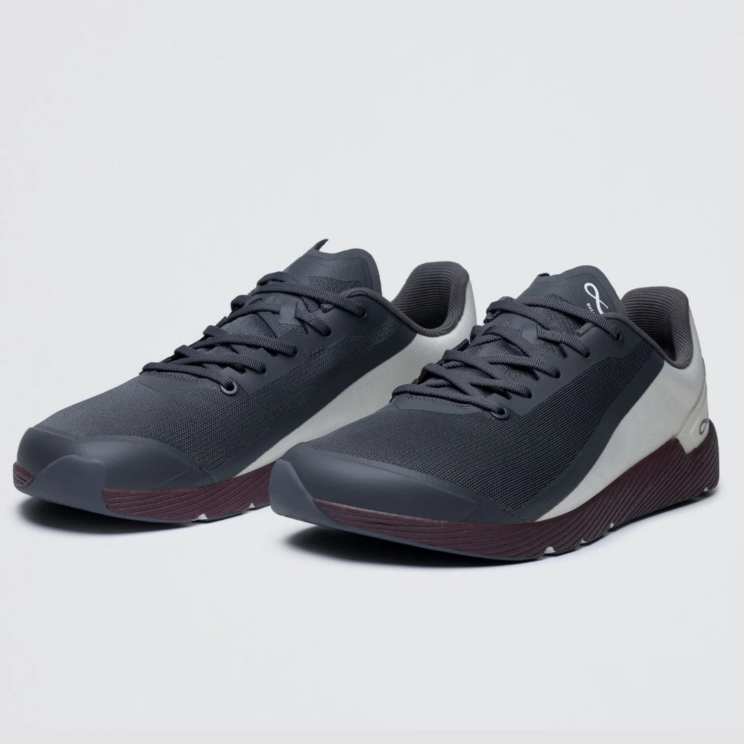 Introducing the Notace Michi 1 (Men’s): a pair of black and gray athletic sneakers with dark brown soles, showcased on a light gray background. These shoes feature a breathable mesh upper and lace-up design, offering an ideal lightweight choice for road to gym wear. The eTPU midsole delivers enhanced comfort and support with every step.