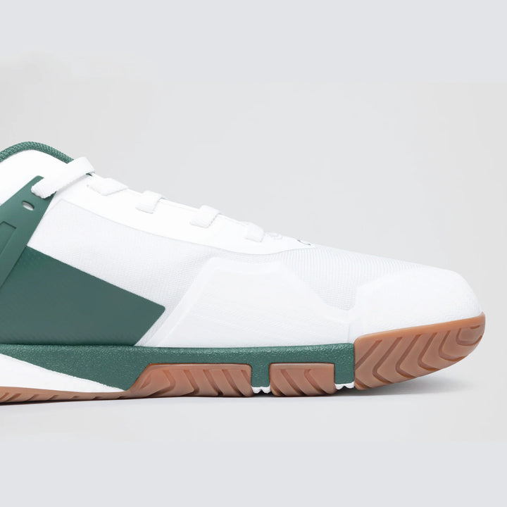 A close-up side view of the Notace KOTO 1 (Men's) court shoe in white, featuring green accents, a green heel sole, and a brown rubber outsole for multidirectional control against a plain light gray background.