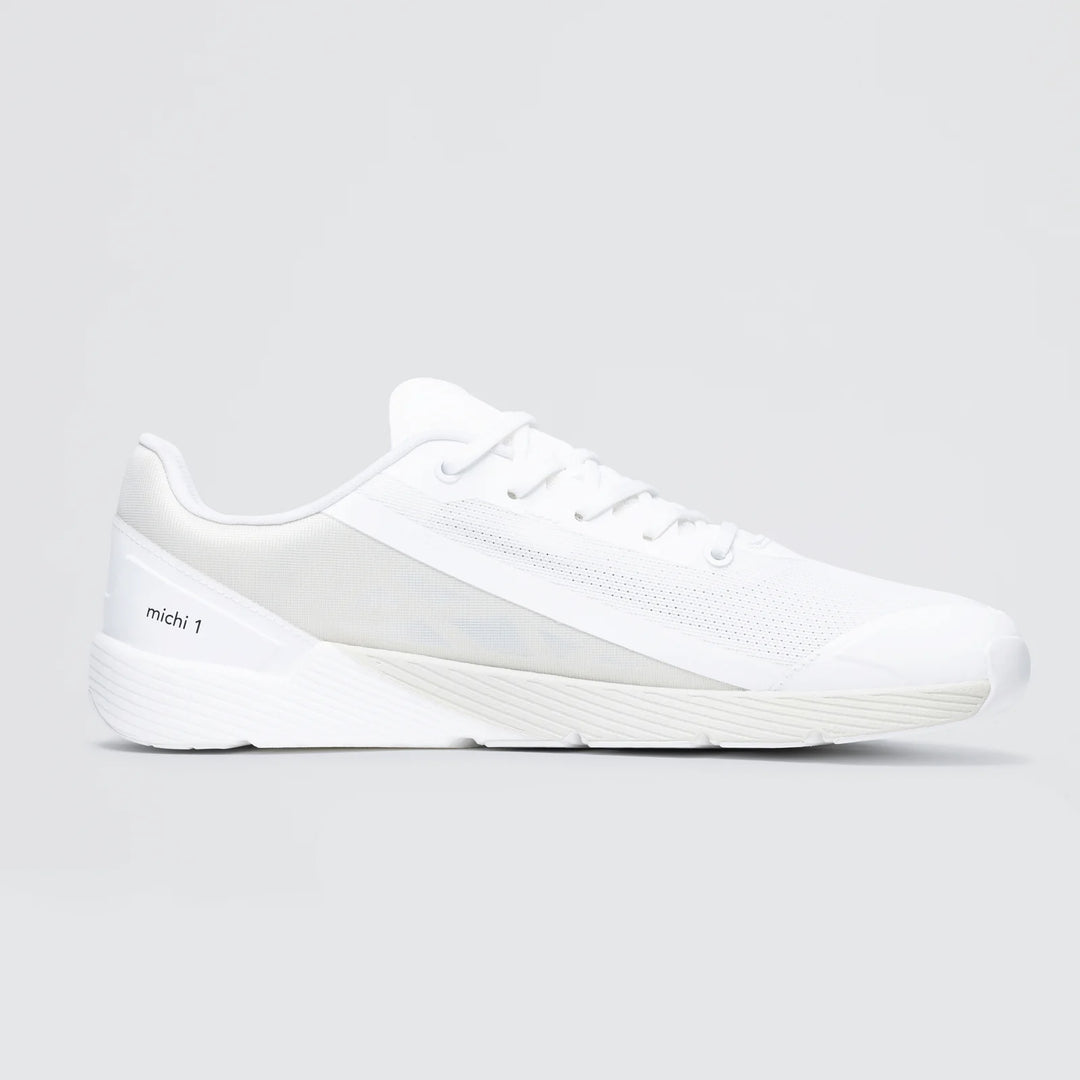 The Notace Michi 1 (Men's) is a white athletic sneaker with a mesh upper, white laces, and a textured rubber sole. "Michi 1" appears on the heel. Its minimal design stands out against a light gray background.