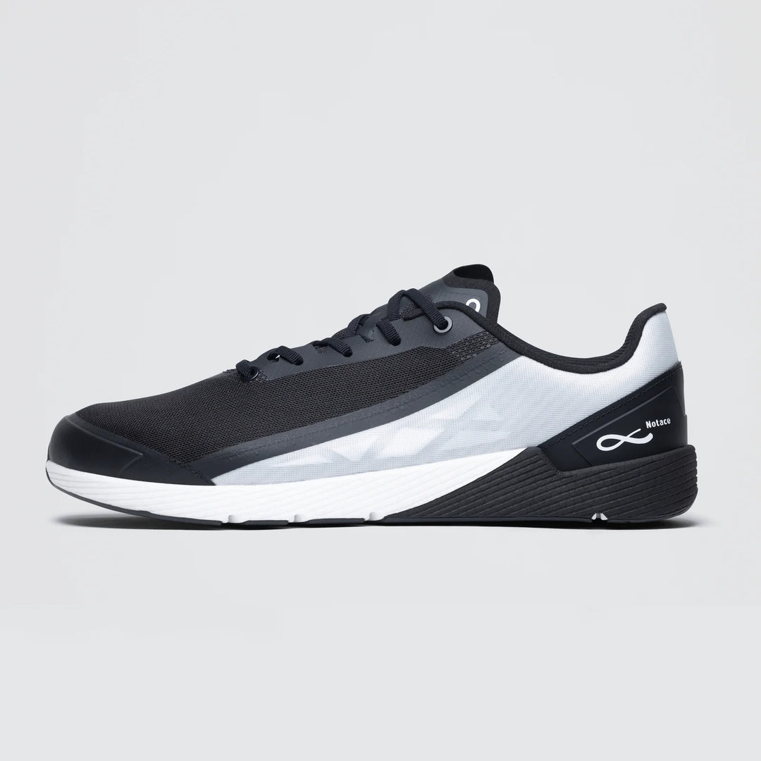 The Notace Michi 1 (Women's) is a black and white low-profile athletic sneaker with a gradient white midsection, black toe and heel, eTPU midsole for comfort, white sole, and subtle branding on the side and heel. Shown on a plain gray background.
