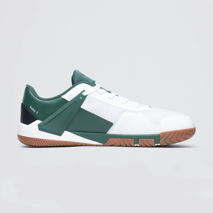 The Notace Koto 1 (Women's) is a low-top court shoe with a white upper, dark green accents, gum sole, geometric design elements, padded collar, "koto 1" heel text, and built for multidirectional stability.