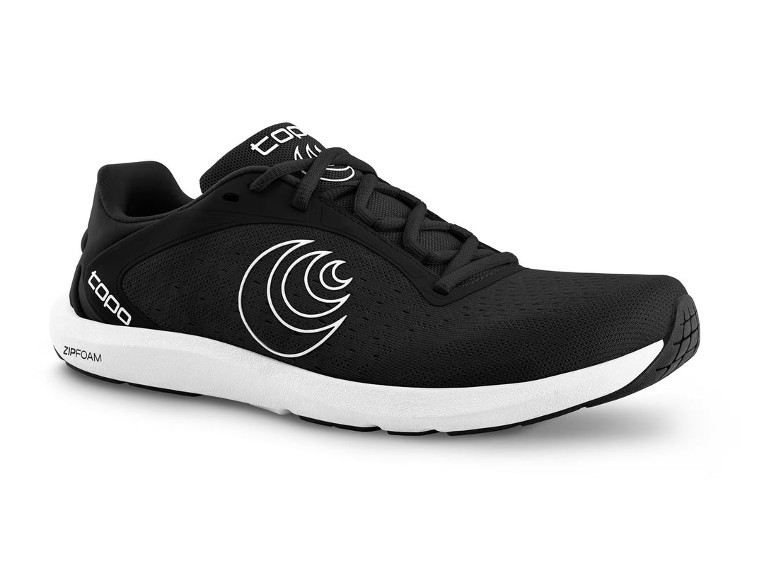The TOPO ST-6 (Women's) is a black athletic running shoe with a white curved line on the side, white sole, and black laces. It features a roomy toe box for comfort and displays the TOPO brand on the tongue and heel.