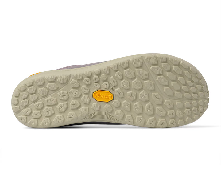 Close-up of the beige rubber sole of the TOPO Connect (Women’s) minimalist shoe, featuring a hexagonal tread pattern and a yellow Vibram logo in the center, highlighting its durable Vibram outsole.